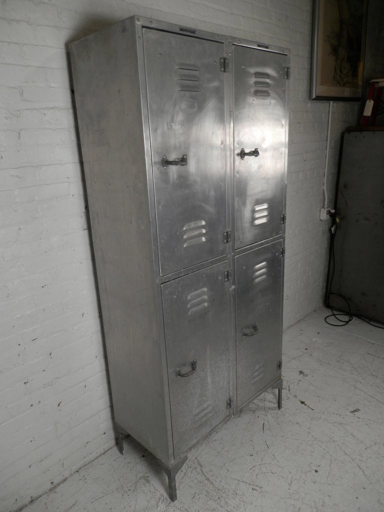 This large aluminum metal locker made by the A.F. Jorss Iron Works has four doors and eight mini shelving compartments inside. Each door has a locking handle. An unusual industrial metal piece.