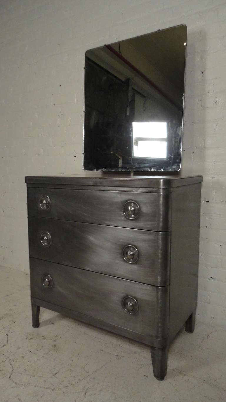 Three drawer metal dresser with large mirror designed by Norman Bel Geddes for Simmons. Piece has been striped and lacquered giving a handsome industrial look.

34w 19d 66h (w/ mirror) 35h (w/out mirror)

(Please confirm item location - NY or NJ
