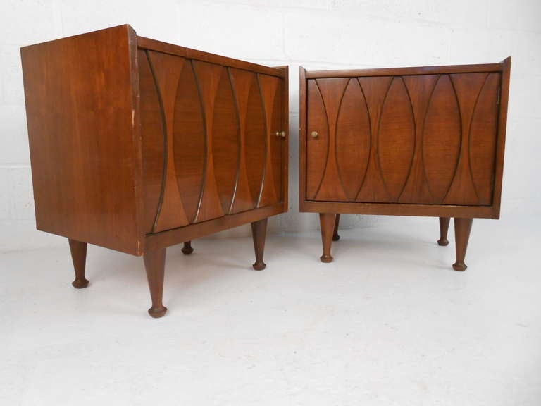 Stylish pair of midcentury American walnut nightstands by Hoke Wood Products make a unique addition to any interior as nightstands or end table. Spacious storage cabinets, unique drumstick legs, and sculpted decorative fronts add to the appeal of