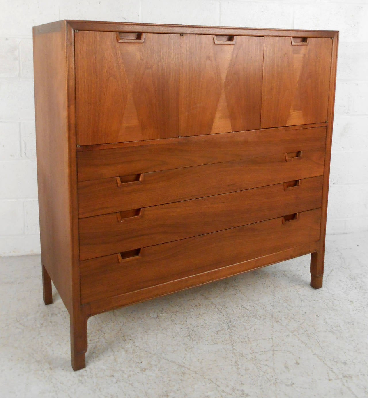 This beautiful Mid-Century high boy features unique cabinet or shelf storage set atop spacious drawers. Complete with John Stuart emblem, this beautiful piece is set apart by its substantial construction and unique drawer pulls. Please confirm item