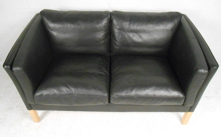 Plush black leather two-seat sofa on light beech legs makes a stylish Scandinavian Modern addition to any seating arrangement. Rich black leather upholstery makes this a great combination of comfort and style. (Please confirm item location - NY or