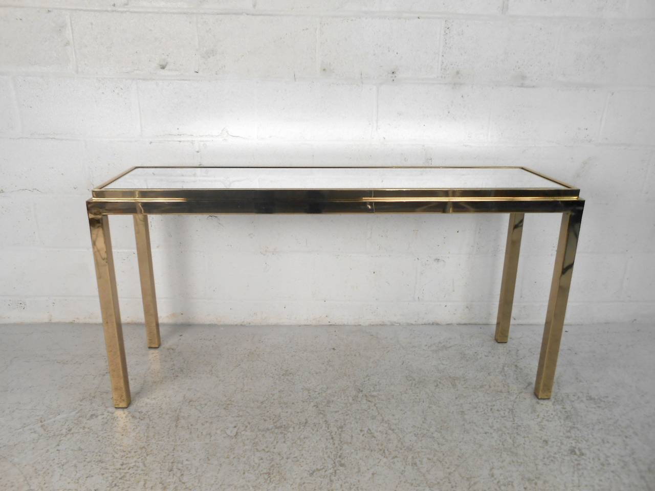 This unique console table features a beautiful brass finish and beveled mirror top which make this a fantastic accent piece for any room. Please confirm item location (NY or NJ) with dealer.