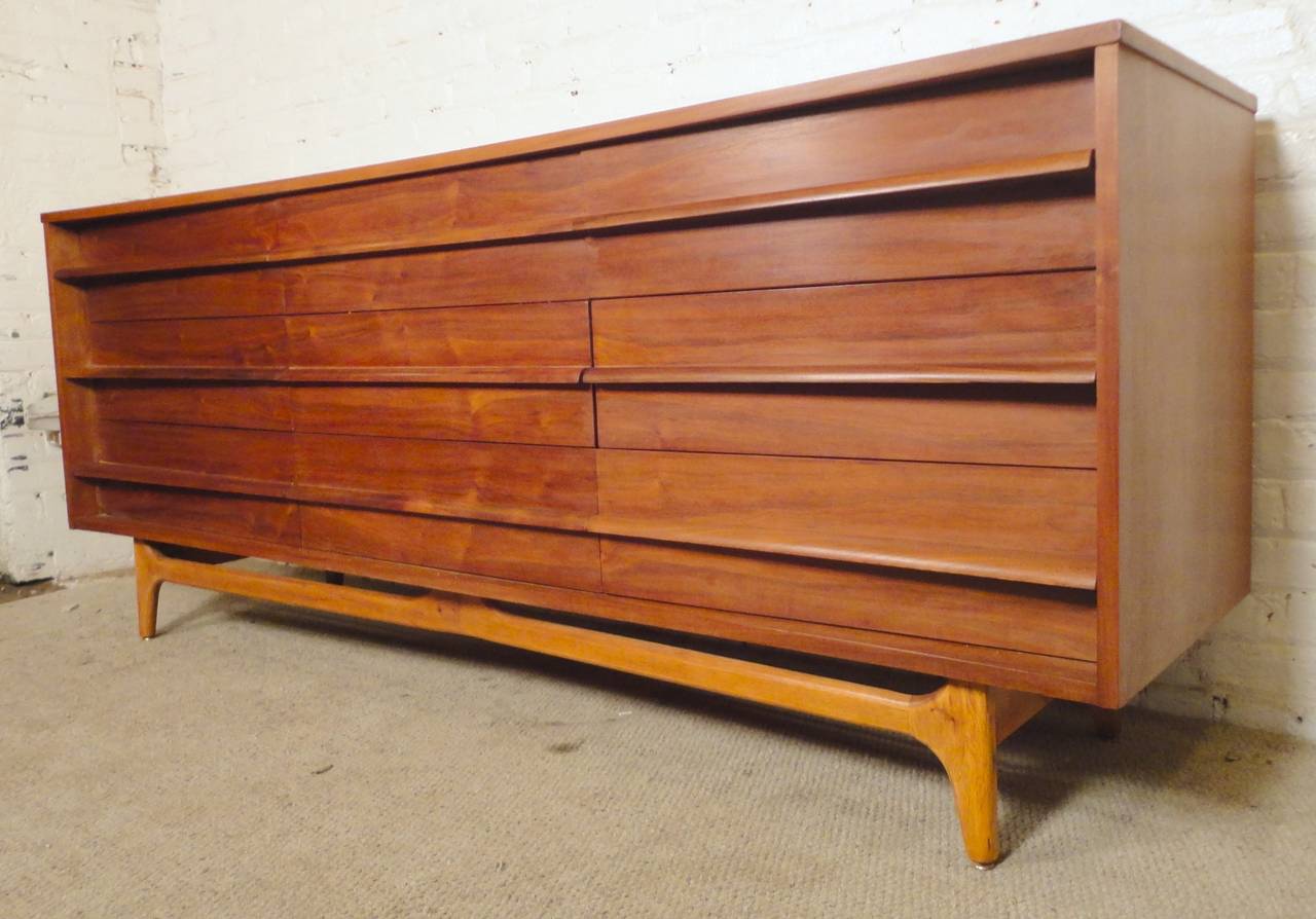 Beautiful nine drawer dresser with wild sculpted front and exciting bowed lines in the style of Edmond Spence. Lovely walnut grain, sculpted handles and tapered legs and base support.

(Please confirm item location - NY or NJ - with dealer)