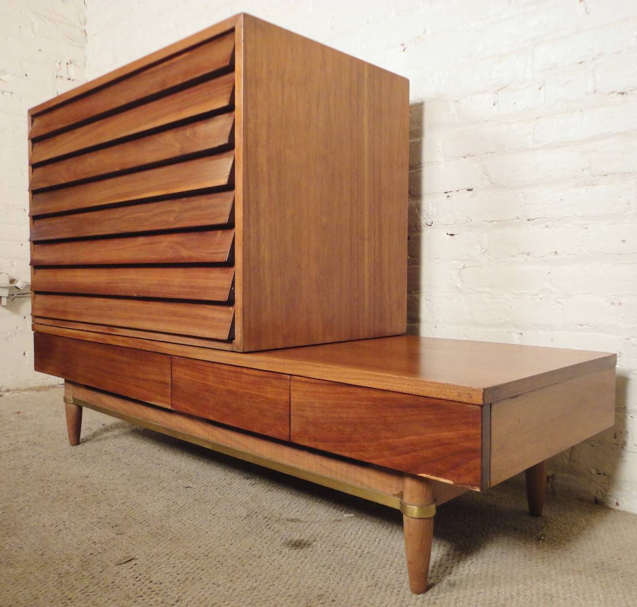 Mid-Century Modern unit by Merton Gershun for American of Martinsville's Dania Series. Features a three-drawer coffee table base with tapered legs and brass runner, three-drawer dresser with unusual louvered front and warm walnut grain throughout.