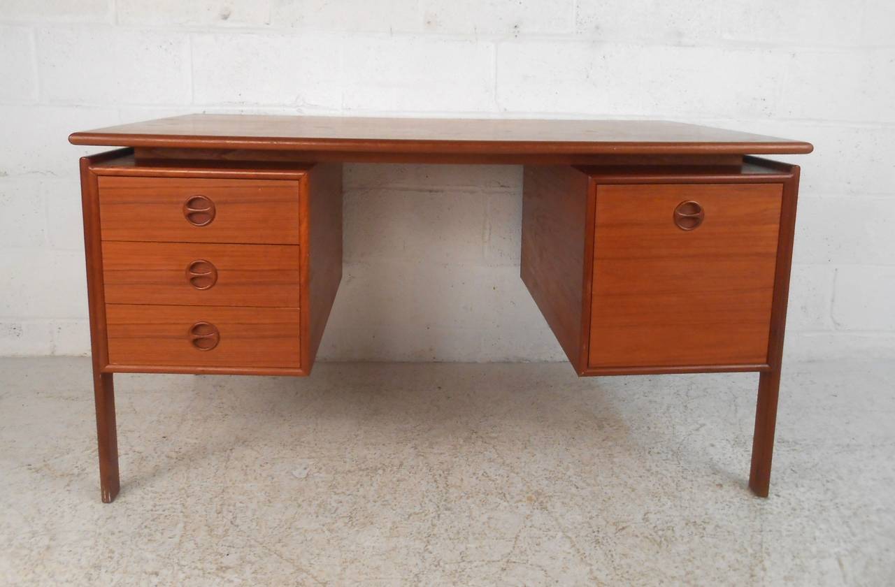 This vintage teak desk by Art of Furn of Denmark features unique drawer pulls, a lovely floating desk top, and sleek finished back. Perfect addition to home or business, please confirm item location (NY or NJ).