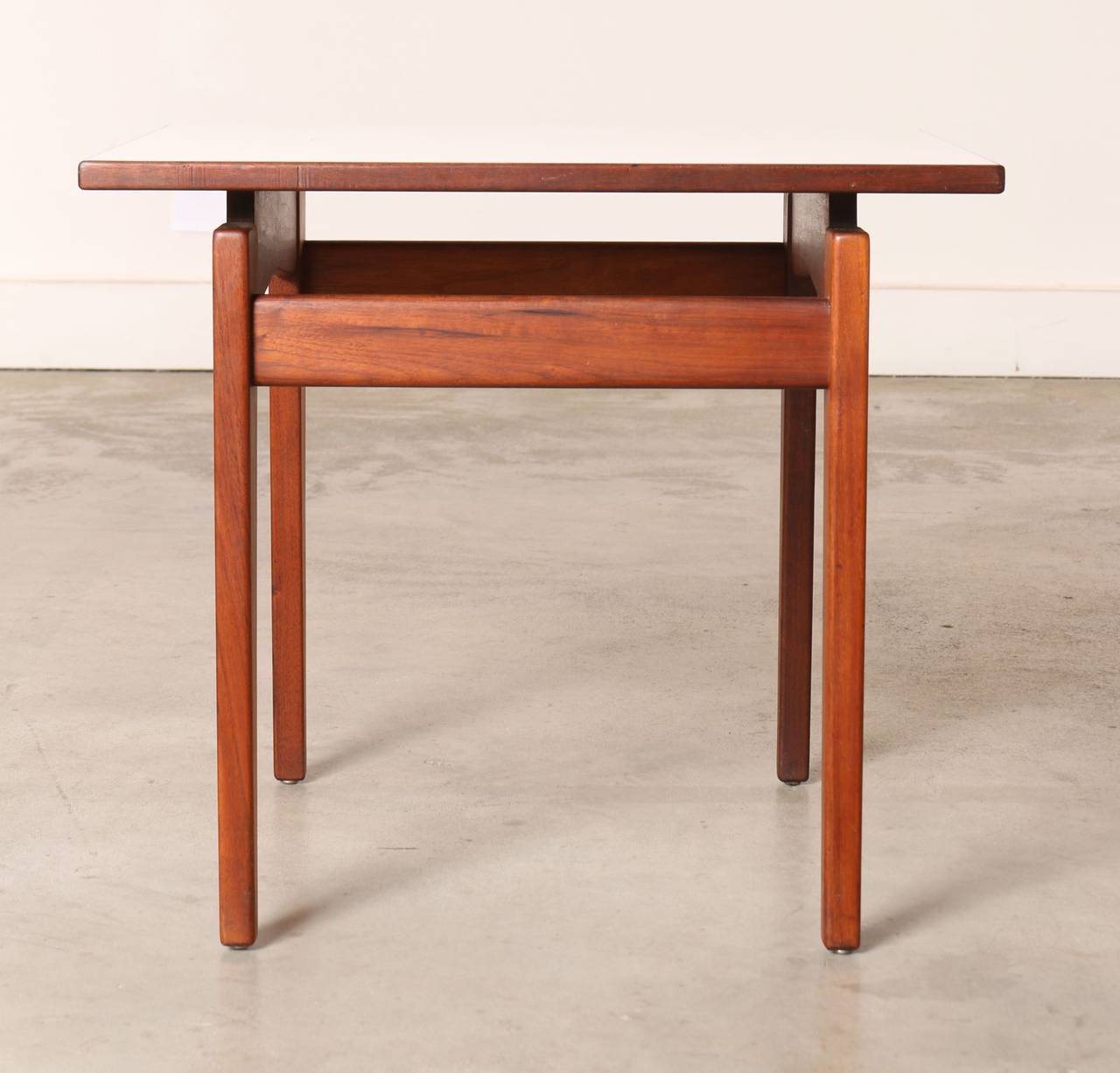A stunning example of Jens Risom's artistry and craftsmanship. This side table by Jens Risom, Risom Design features a solid walnut frame and a walnut and white formica floating top that appears to be detached and floating. 

Recognized as a