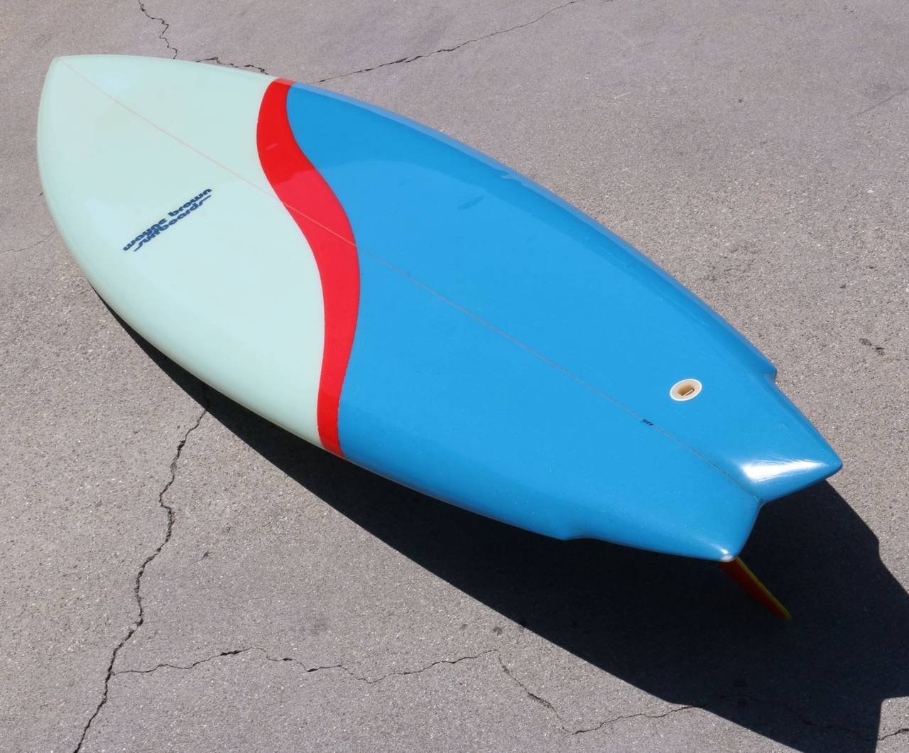 The energetic shape of this stunning surf board is made even more visually exciting by the maker's vibrant use of color. Bright royal blue and subtle sea foam green are accented by a cherry red band cascading across the board.

At 6 foot, 6 inches
