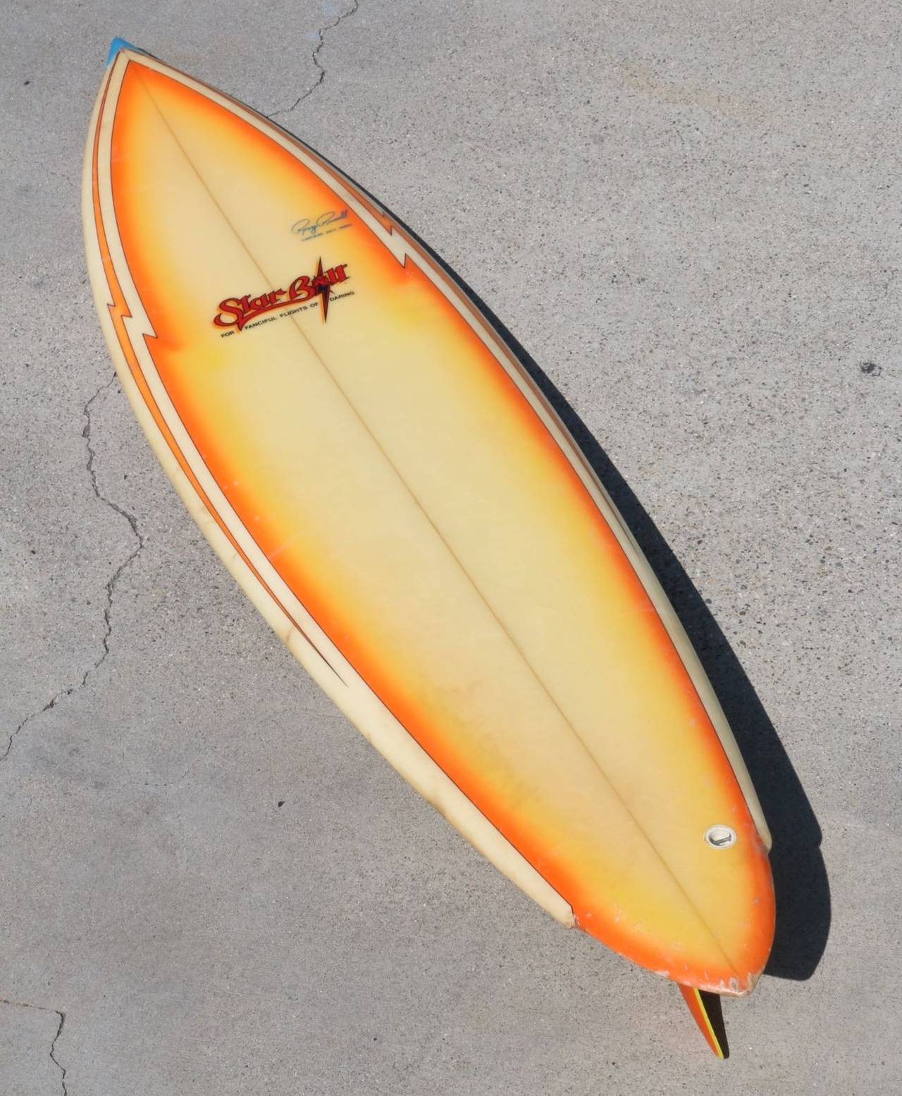 “Star Bolt - For Fanciful Flights of Daring” is emblazzoned on the front of this 6’ surfboard. The shape, the size, the color and the graphics all contribute to the vision we have of this baby flying across the water - even as we see it hanging on