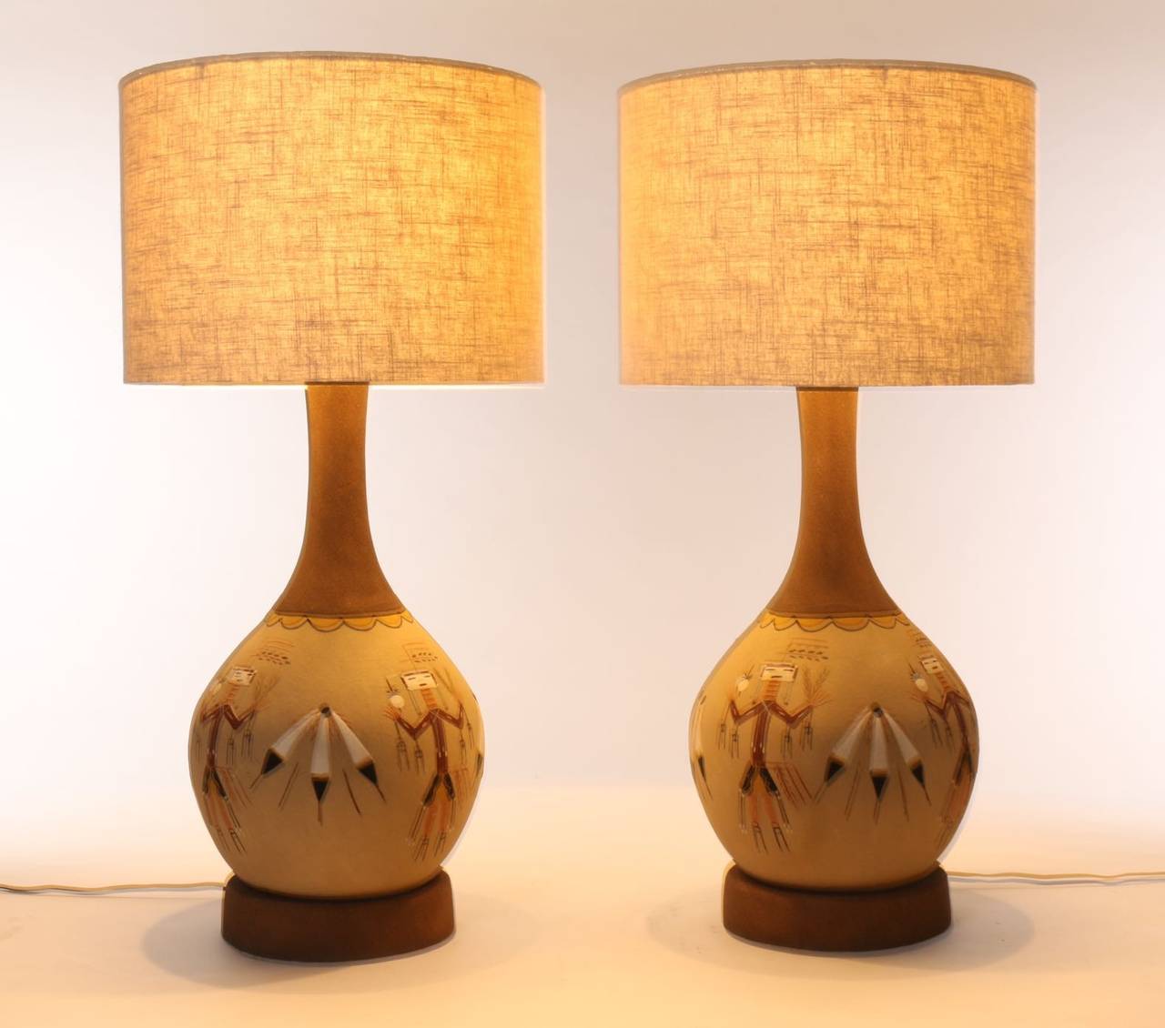 Striking Native American Artistry captures Yei (Yeibicheii - the Holy People) figures, feathers and the lure of the South West. This 1960s table lamp pair was created as a commercial representation of the sacred art of Native American sand painting