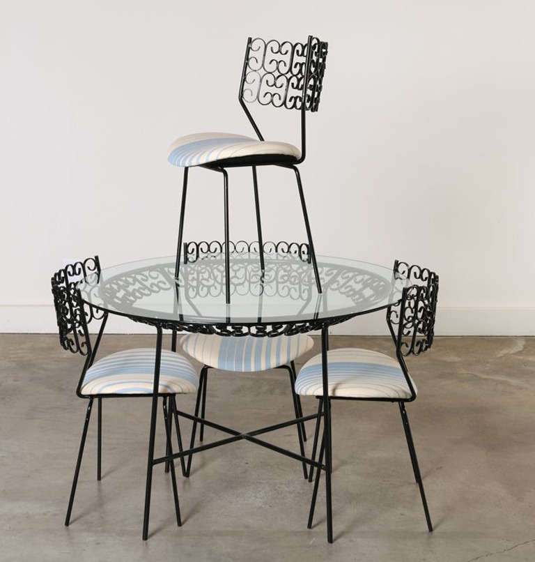 This round wrought iron table and four matching (and comfortable) chairs are perfect for the patio or garden. This set features quality hand hammered wrought iron craftsmanship.  The table has new glass and chair seats have been  reupholstered in a
