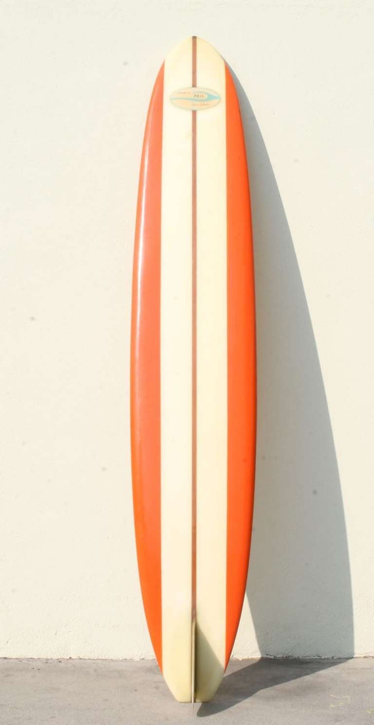 Phil Surfboards Downey CA
This is a magnificent longboard.  An early 1960's semi gun, pointed at the front and narrower at the back for riding larger waves, it has a 3/4 inch redwood stringer flanked by creamy-white, and on the edges, bright