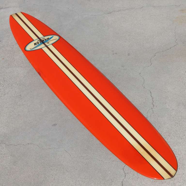 Beautiful giant logo Hansen surfboard in vibrant orange and clear center stipe surrounding a 1