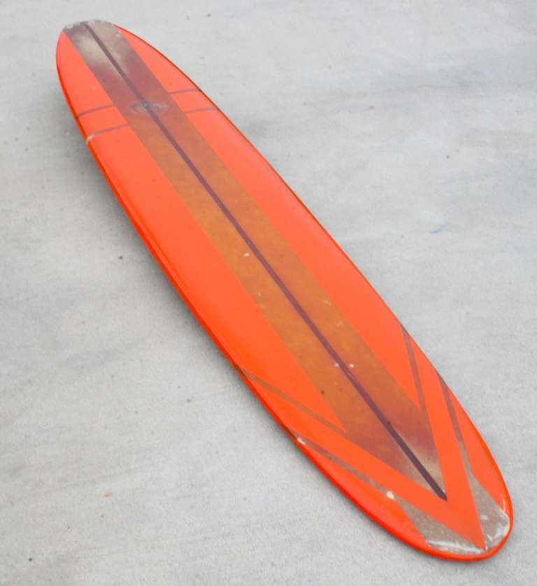 Well worn, well used, a great survivor.
South Bay Model manufactured by Titan Surfboards, Santa Ana California in 1964
Bright orange longboard with stripe and arrow design on nose and 3/4 inch Redwood Stringer for added strength in the