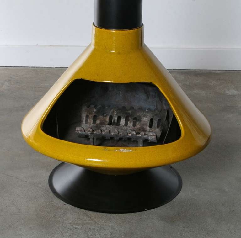 Hard to find Midcentury Ceramic Fireplace in Inca gold.
Complete with spun steel base in matte black, 2 matte black chimney stacks and screen, ceramic base in original 'very good' condition and original iron log holder. 

Base Height =