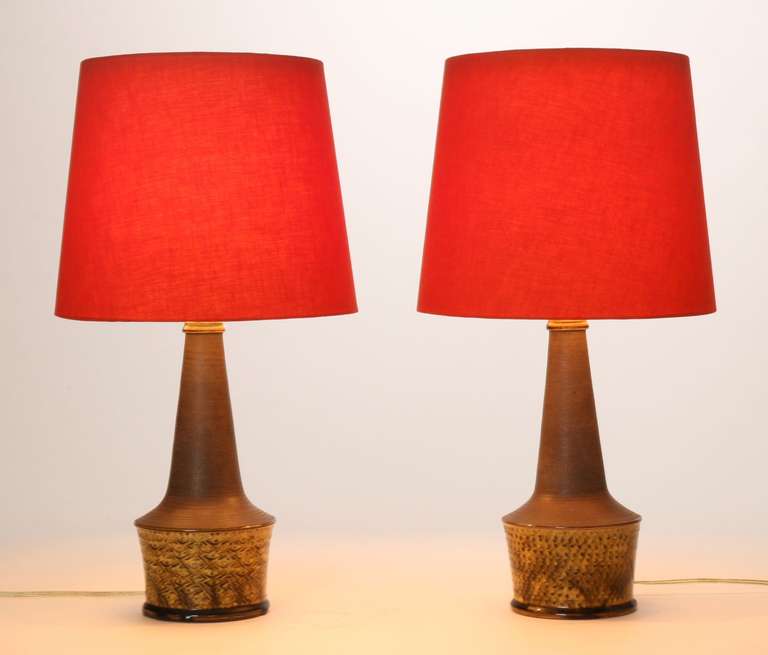 ONE AVAILABLE
1960s Danish ceramic lamps by the Danish potter Nils Kähler (HAK). 
The dimensional glaze is textured and layered with shades of mustard and brown. Red linen lamp shades set off the neutral bases.

 
Hand signed in the ceramic of
