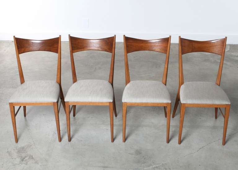 Slim, sculptural and majestic this set of four Paul McCobb bowtie dining chairs are as beautiful as they are functional. Solid walnut wood frames are sturdy and comfortable yet very elegant with a backrest that gently bows, cradling the back and