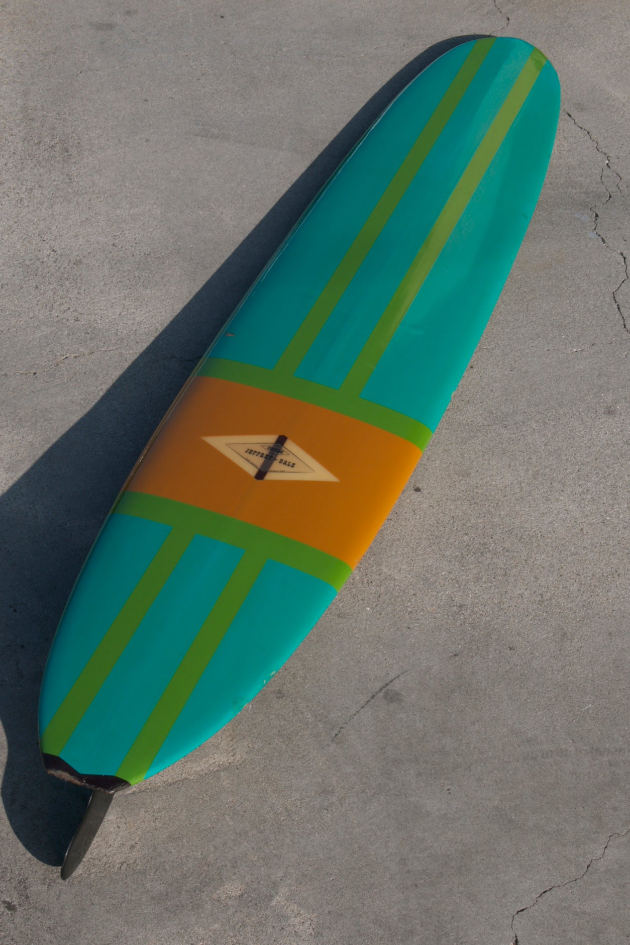 This stunning 1960s surfboard has an older restoration featuring shades reminiscent of the fantastic Porsche colors of the 1960's.  Eye catching yet subtle stripes of pea green and sea foam blue are laid over a pumpkin orange center.  The clear logo