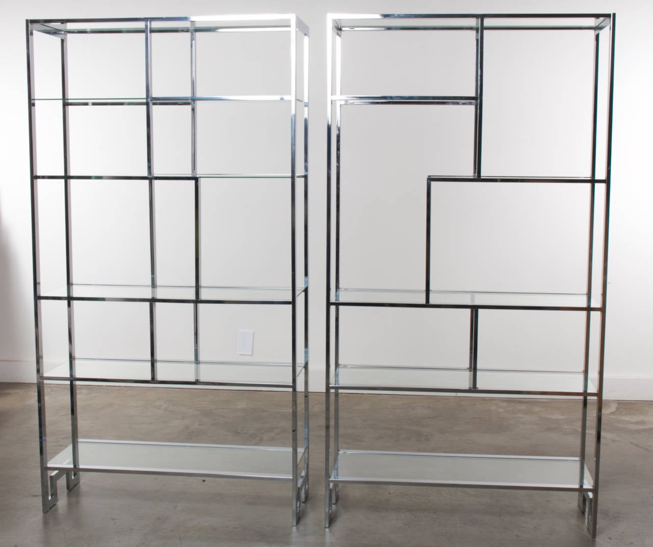 Geometrically shaped chrome frames are accented by glass shelves in this pair of vintage chrome etageres shelves by Milo Baughman for Thayer Coggin.  Made in the 1970's, each unit features a unique shelving configuration presented in matching chrome