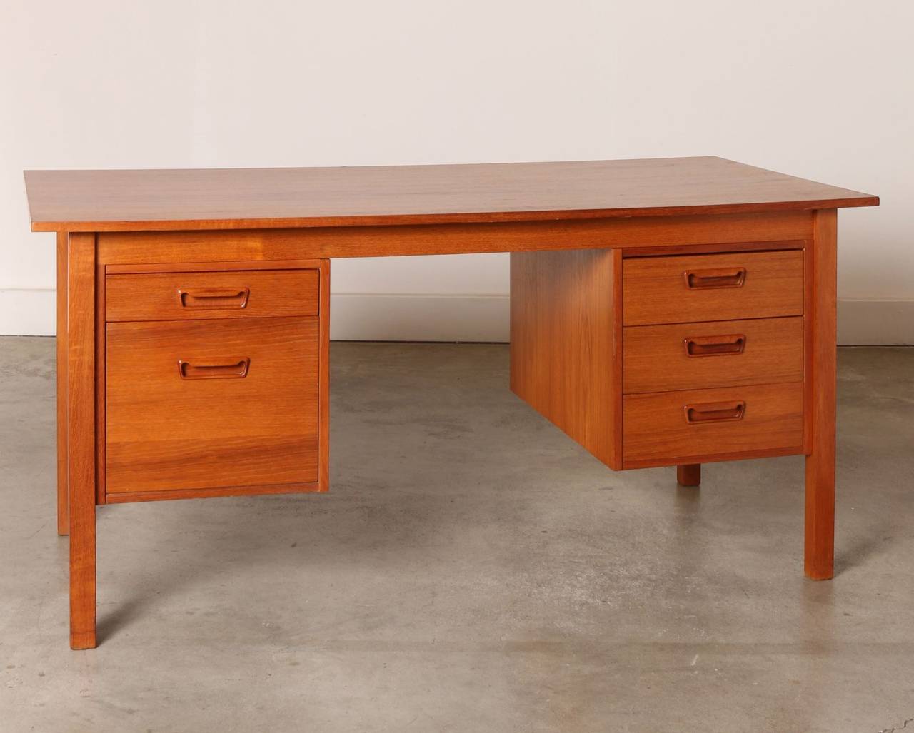 Float this substantial desk centrally in a room or position it near a corner or wall. This two-sided Danish Modern teak partners desk features five drawers (one of which holds file folders) on one side and bookshelves on the other. 

The drawers