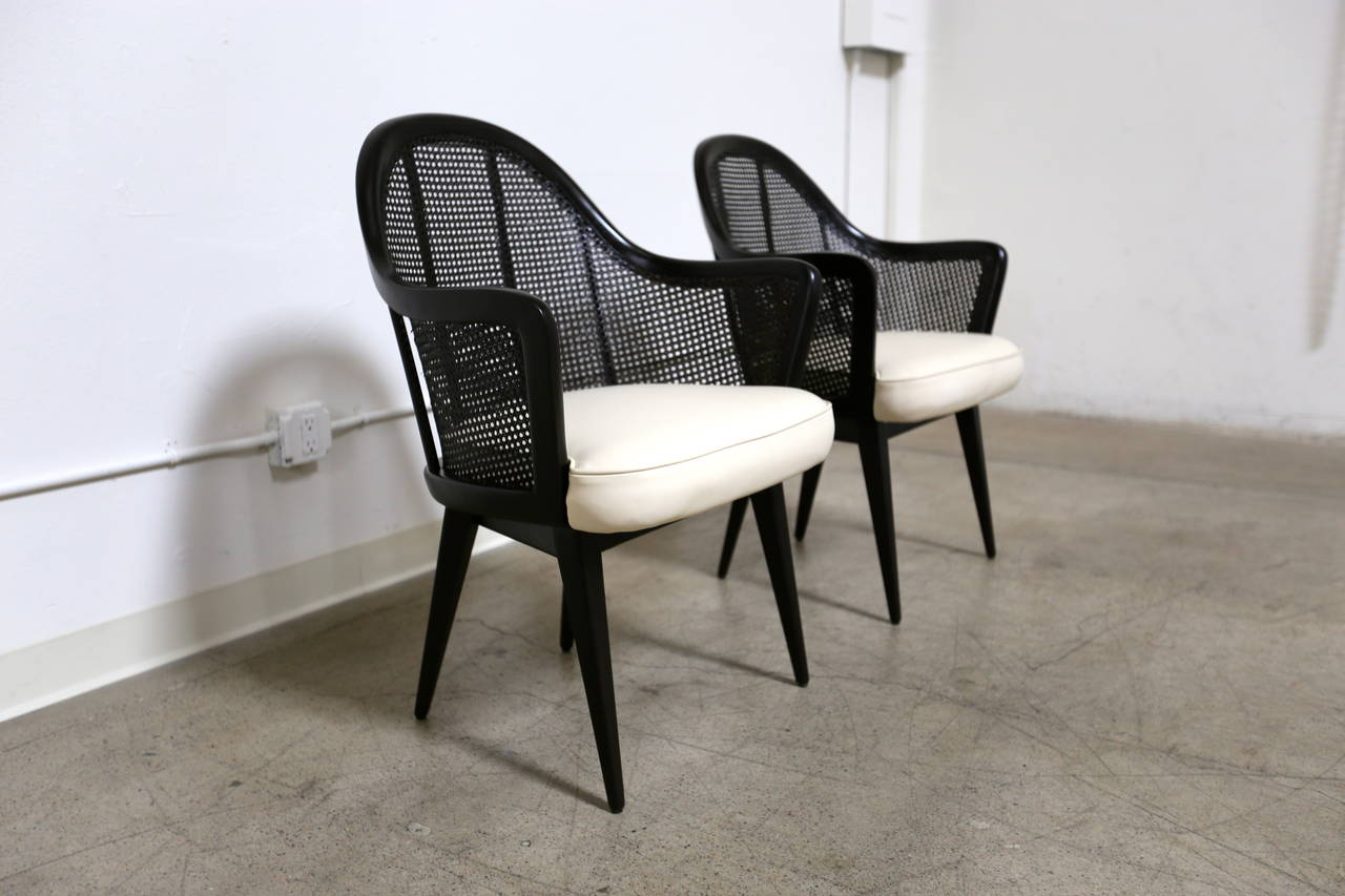 Pair of ebonized caned back armchairs by Harvey Probber. The seats are a light cream colored leather.