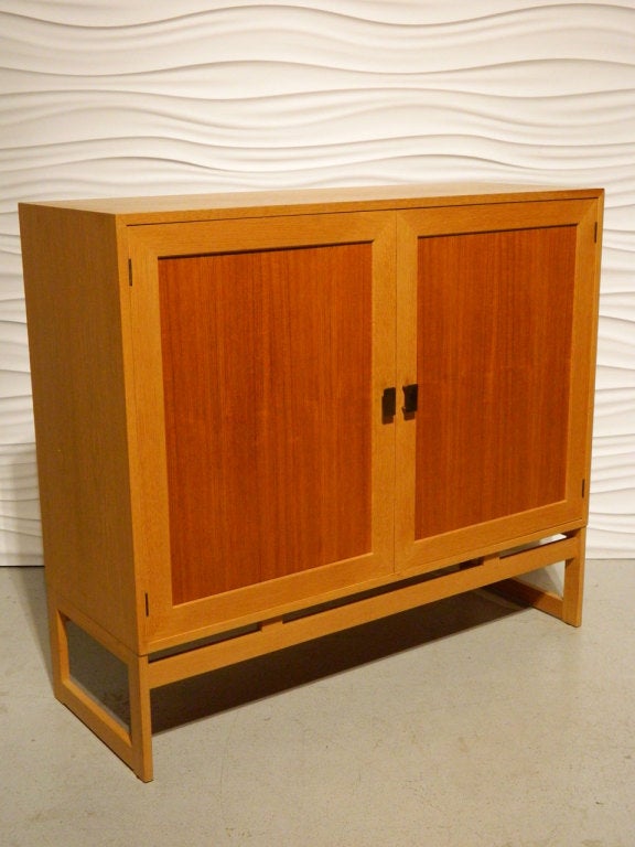 This Swedish mid-century modern linen press features open shelving behind two-tone teak and oak doors.