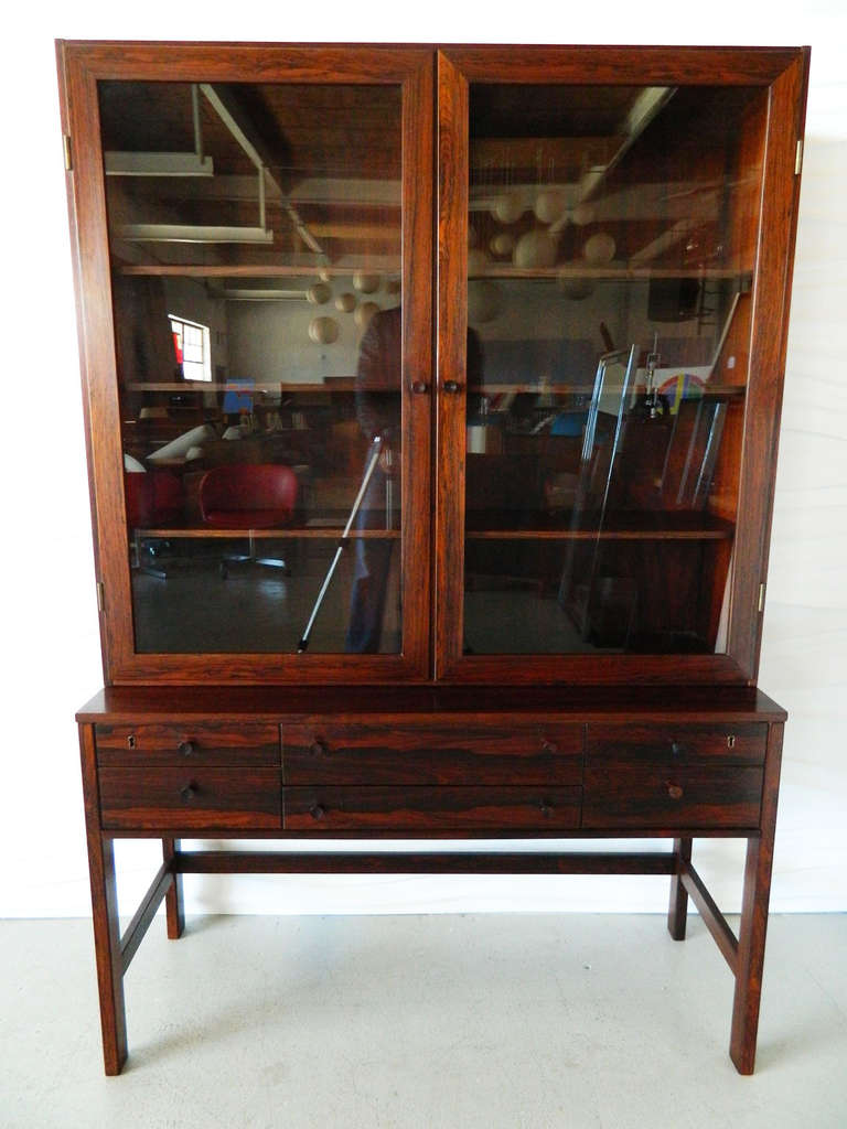 This stunning Danish rosewood two-piece cabinet by Lovig has a base with six  drawers and a glass-enclosed hutch with adjustable shelving. The wood has a beautiful active grain. Made in 1968.