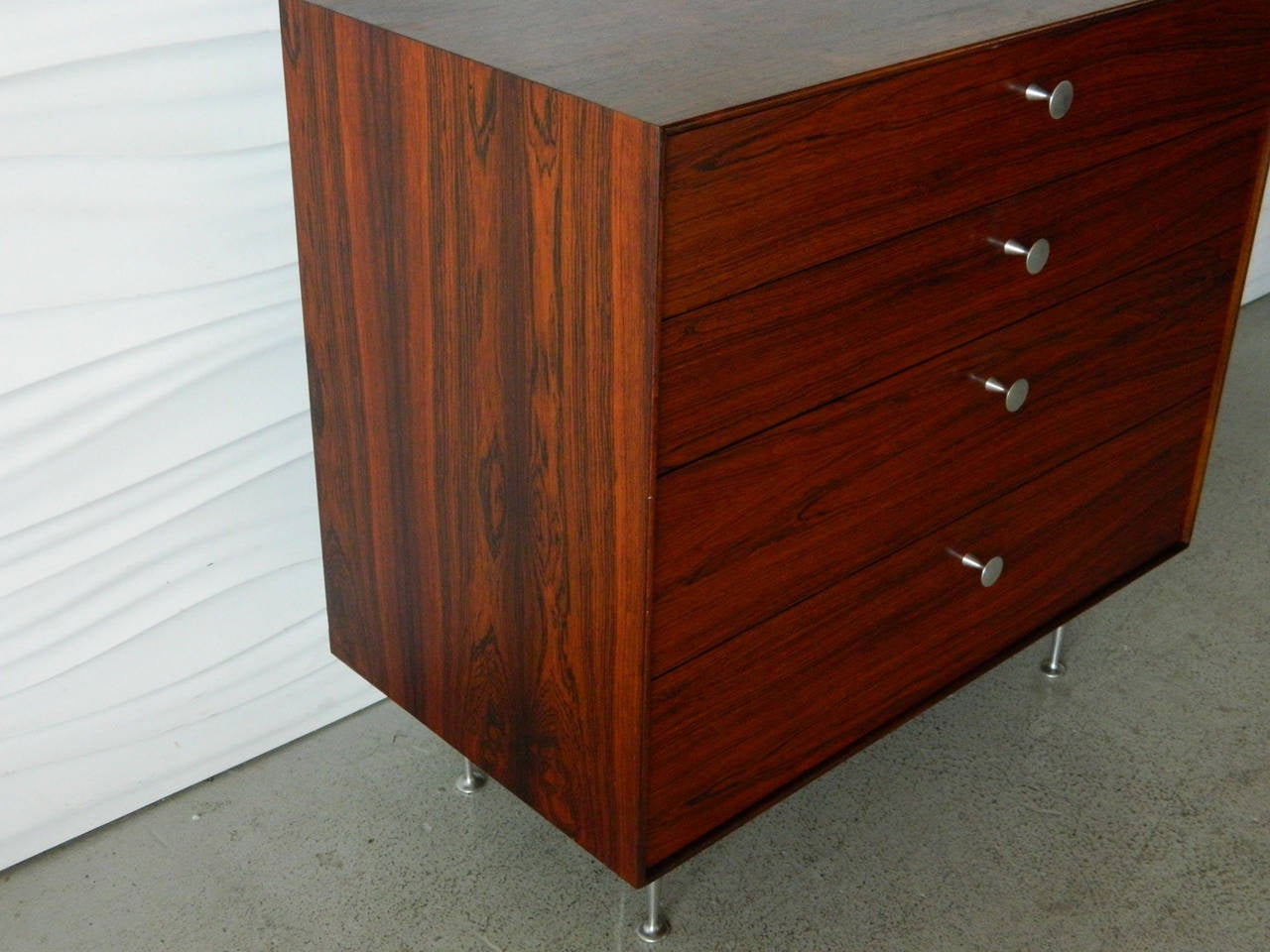 Gorgeous four-drawer rosewood chest of drawers from American designer George Nelson's Thin Edge series for Herman Miller. The top drawer has a built-in vanity mirror. 

Two additional rosewood chests are available to create a beautiful trio of