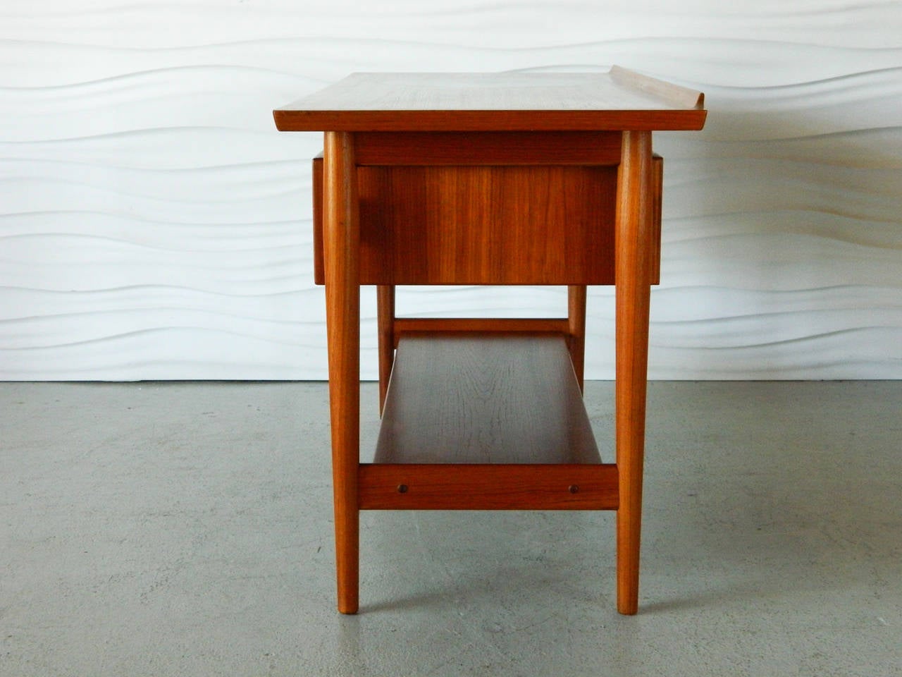 Designed by Danish designer Arne Vodder for Sibast, this handsome teak console has a floating top, four drawers, and a large open shelf. The top surface has a round formica inlay.