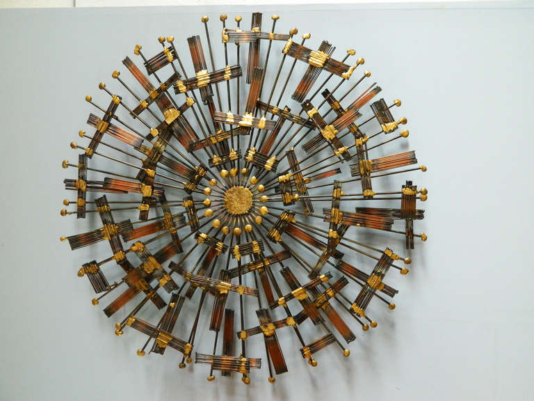 Metal rods highlighted by golden solder radiate from the center of this large, Jere-style sunburst.