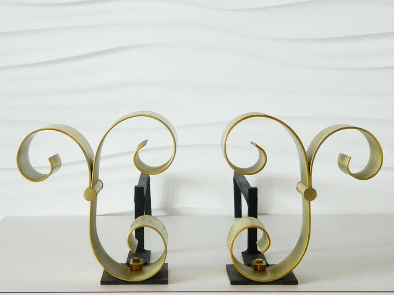 Stunning pair of brass scroll andirons attributed to French designer Raymond Subes.