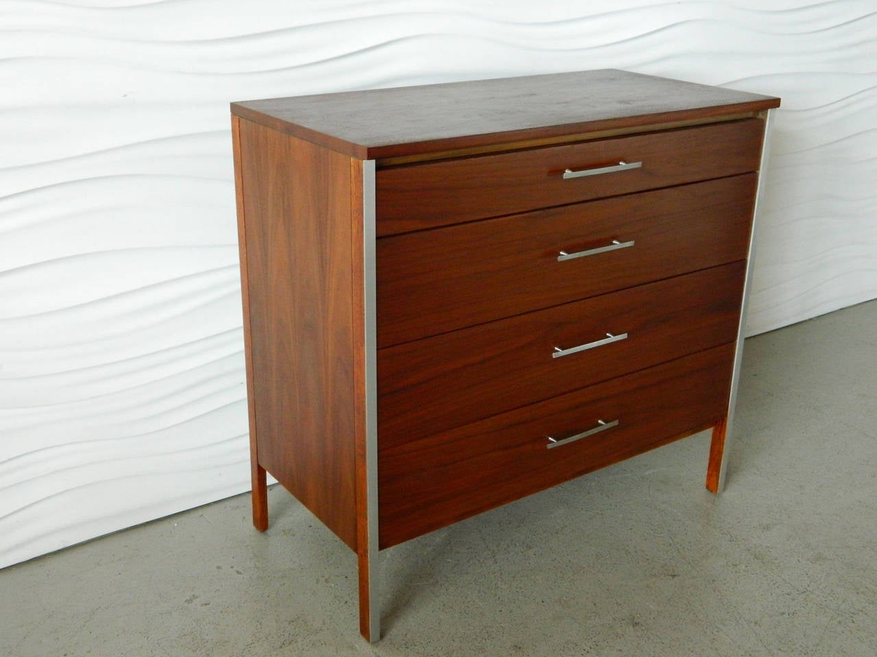 Designed by American designer Paul McCobb for Calvin Furniture, this warm tone walnut chest of drawers has aluminum trim accents and drawer pulls.