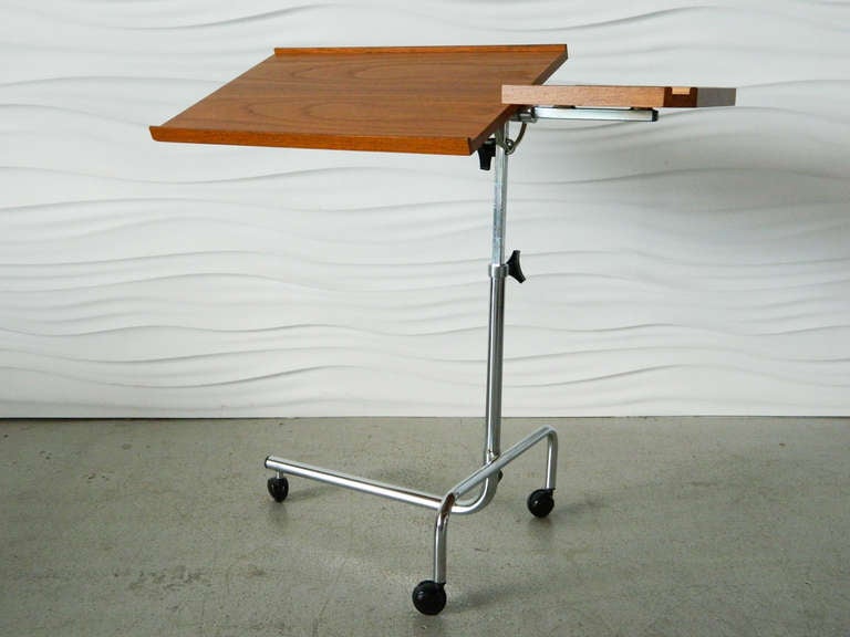 This versatile Danish Modern teak rolling tray table by Danecastle can be raised from 25