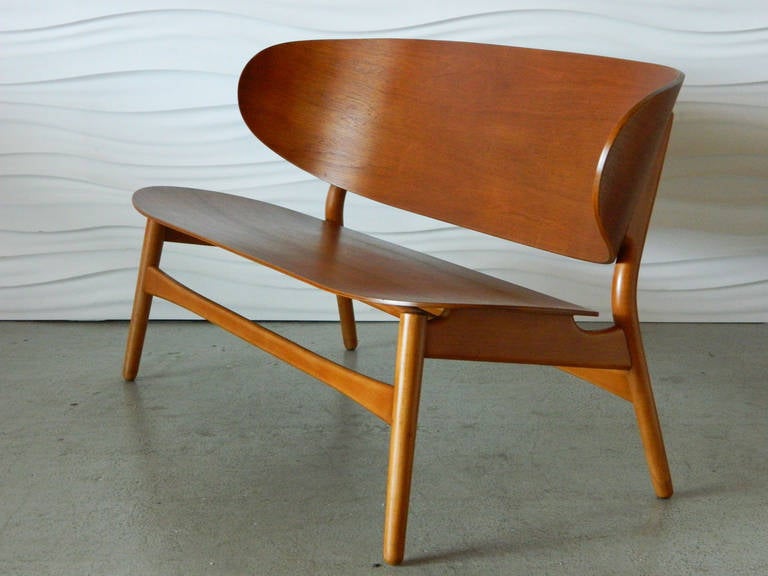 Danish designer Hans Wegner originally created his elegant yet simple shell settee in 1948 using teak and stained beech. The settee was made in Denmark and manufactured by Fritz Hansen.