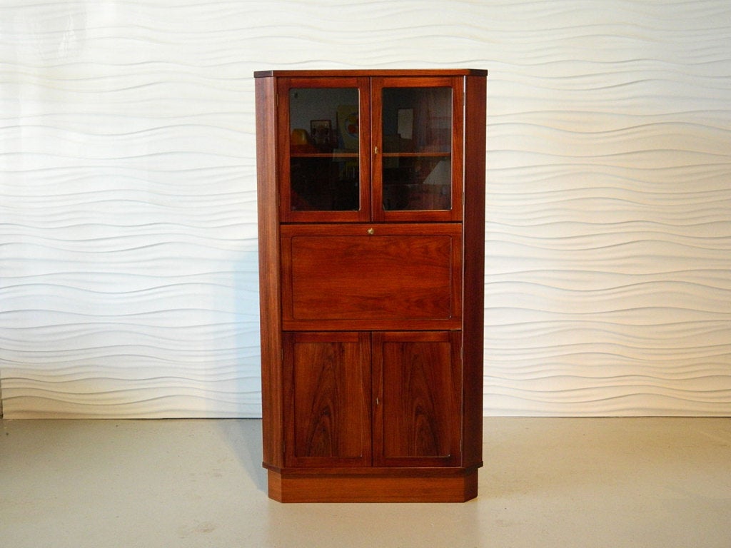 Danish rosewood corner cabinet has a drop front desk with key. Glass-front display and lower enclosed cabinet also have key locks.