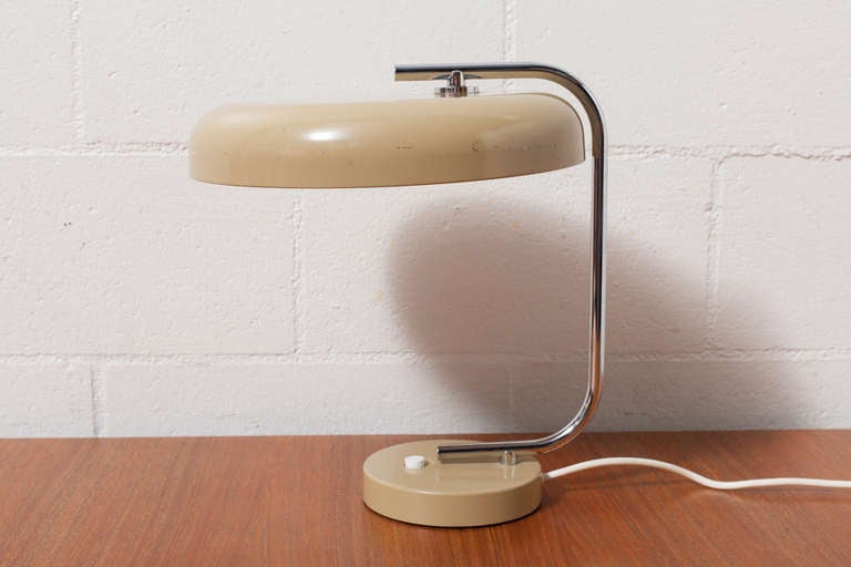 Weighted enameled base and chrome arm holding matching khaki enameled metal pill box shade with large button switch. In good condition, some signs of wear in keeping with its age.