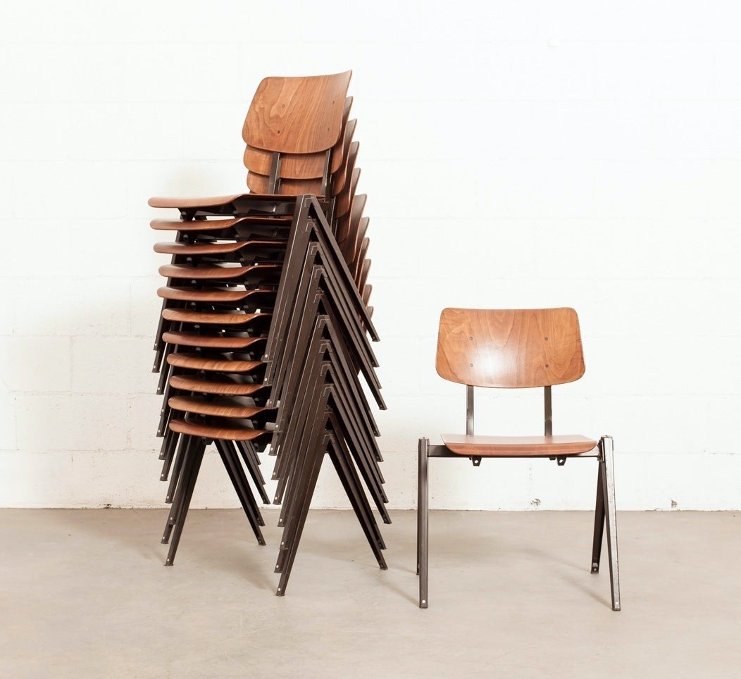 Teak toned seat and back stacking chairs with brown enameled folded sheet metal Prouve style legs.  Frame is in original condition with some wear to enamel frame.