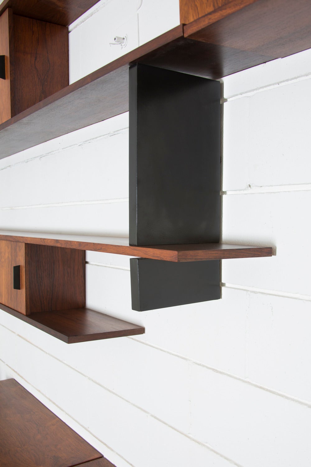Massive floating rosewood wall system with beautiful bookmatched cabinet fronts and black enameled metal pulls on upper cabinets. Upper shelves and cabinets are 9'' Deep and lower cabinets are 17.5'' deep. Unit measured at 11'' from floor. In good