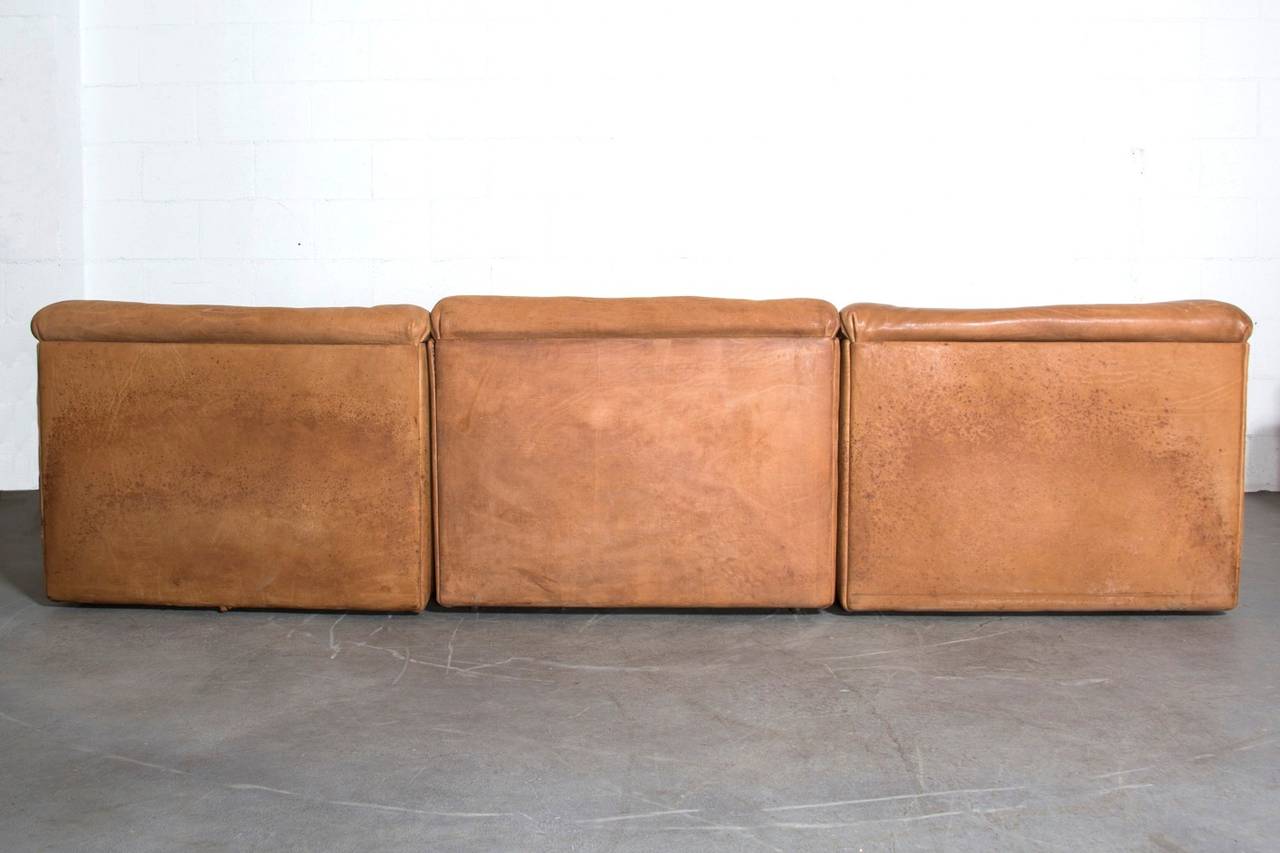 Beautiful three-piece modular sectional sofa in thick buffalo leather by De Sede, Switzerland, 1970s. Another three-piece available. In original condition, leather shows signs of wear, some spot staining visible. One of the side panels is separating