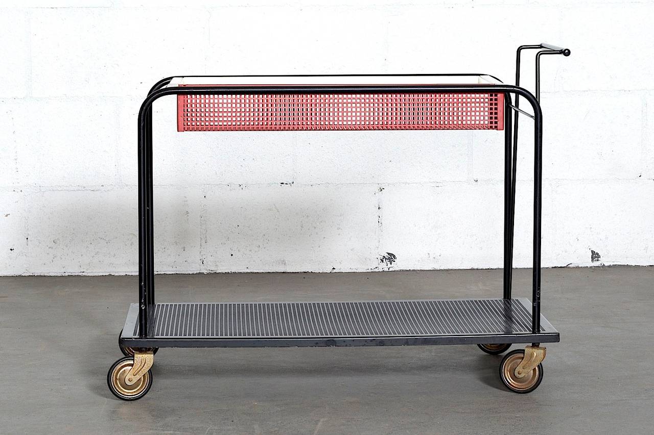 Elegant enameled metal rolling bar cart with removable trays in the style of Mathieu Mategot. Enameled black metal frame with handle and removable white and red-perforated top level trays. Perforated black enameled bottom tray with brass wheels. In
