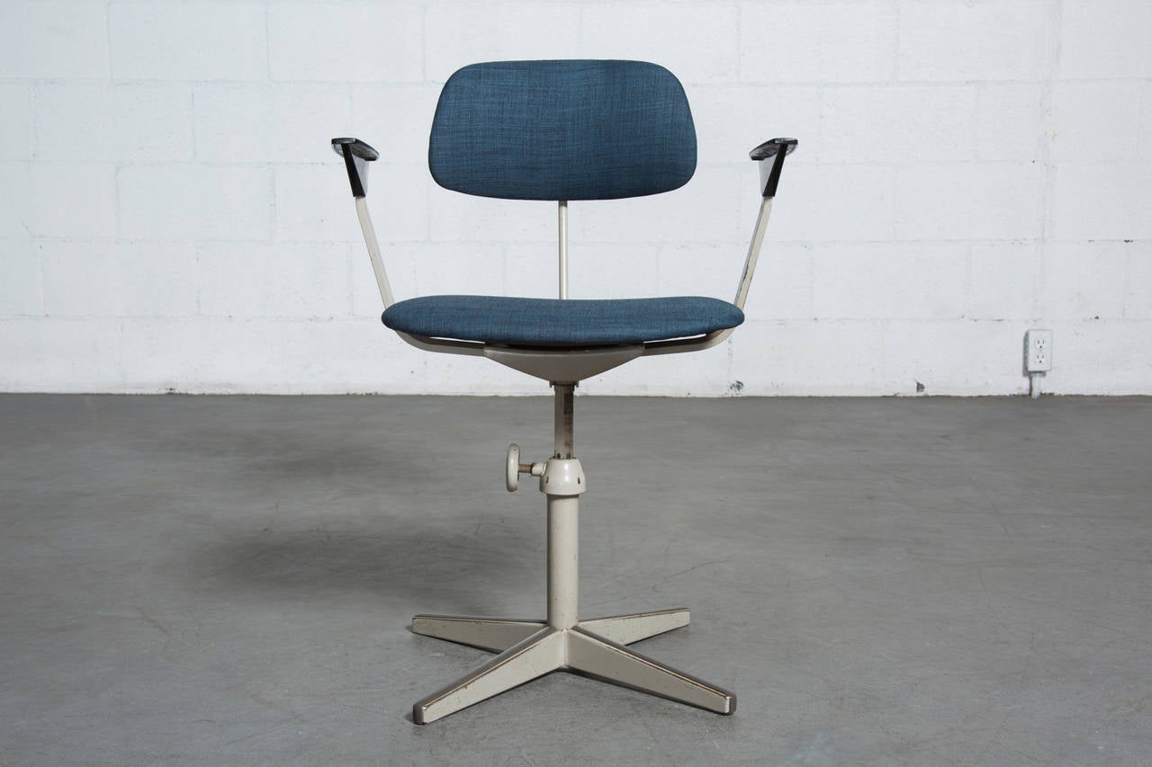 Original Industrial dove grey enameled frame with newly upholstered blue fabric seat and back, with signature original angled bakelite arm rests. Back and seat height adjustable. Knob is engraved 