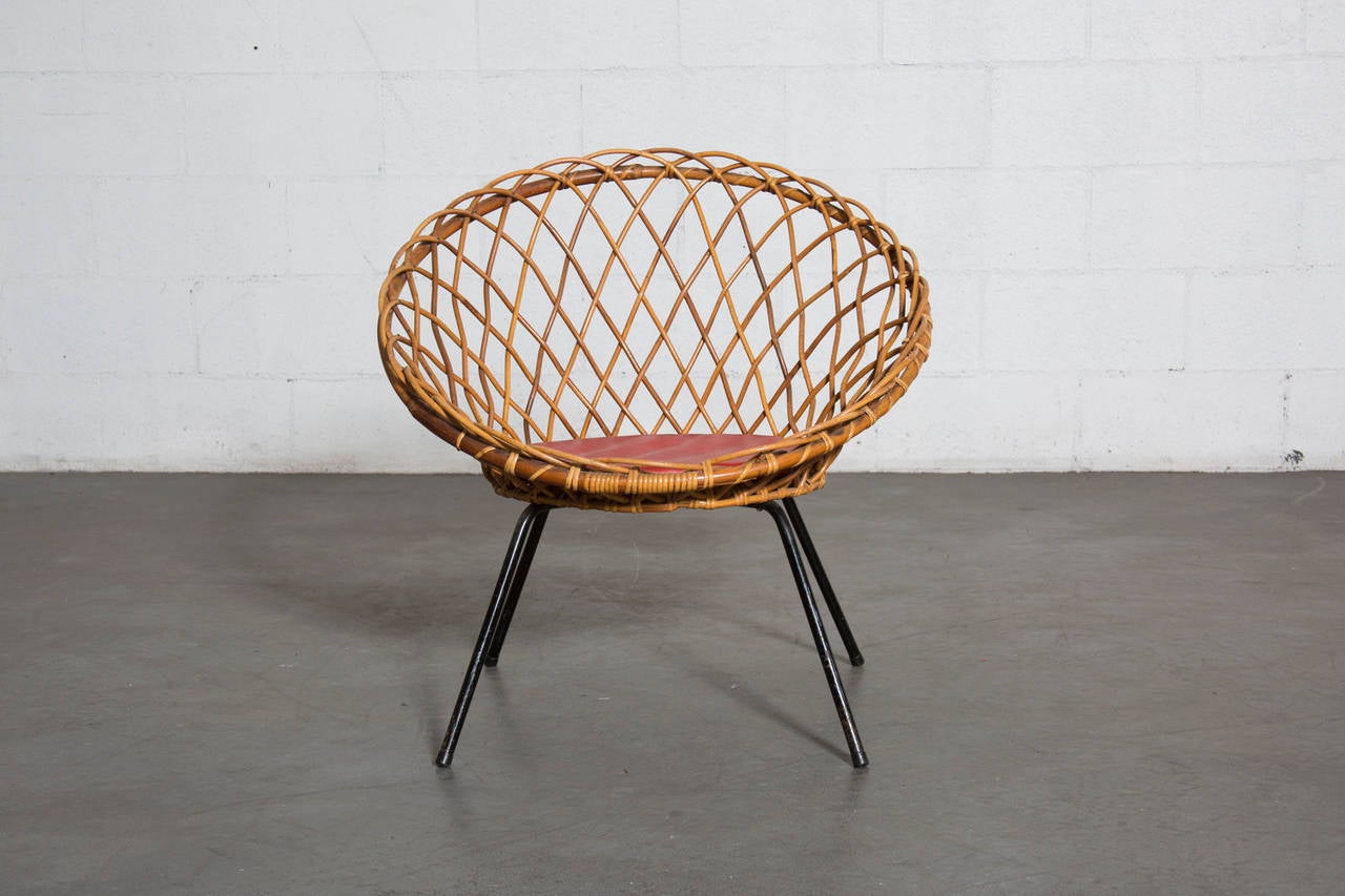 Lattice weave bamboo hoop chair with original red cushion in original condition with some visible wear consistent with age and use.