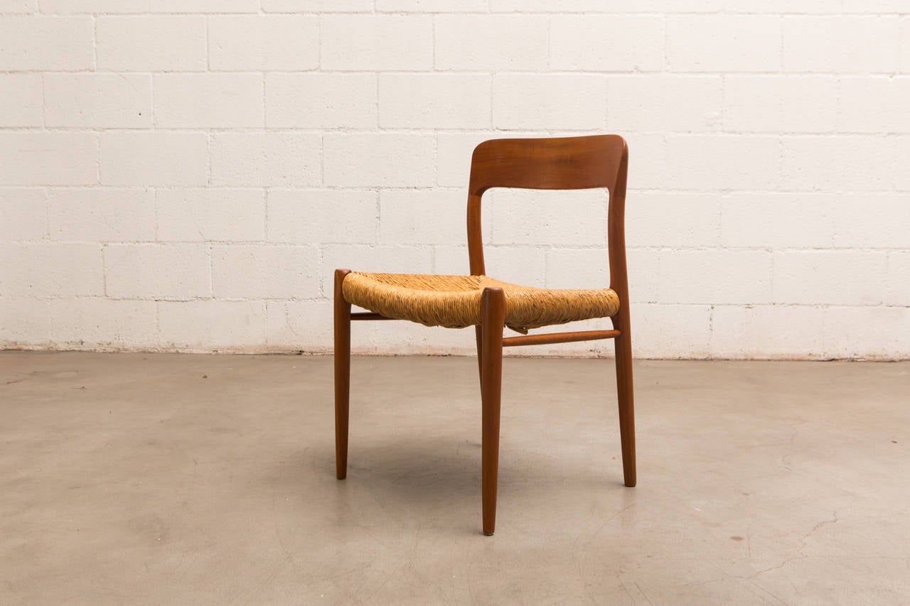 Niels Moller model 75 teak dining chairs with woven rush seating. Beautifully finished wood and grain pattern with curved back. Original condition with some visible wear to the legs and pieces of loose rush.