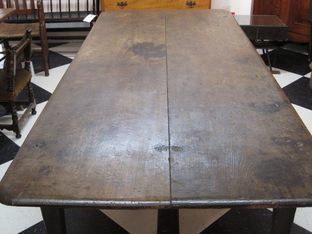 Very attractive large American stretcher-base farm table with a medial stretcher. The table has a two-board poplar top with a beautiful old dark scrubbed surface, original Spanish brown paint on the wooden-pinned base, and tapered legs. Early 19th