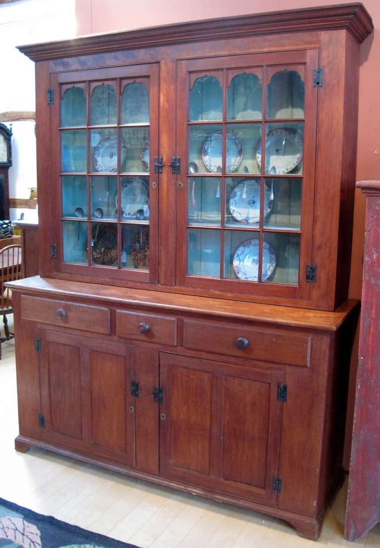 Chippendale two-piece Pennsylvania step-back or Dutch cupboard, cherry, having a bracket base and an attractive wide cornice.

The top section has two glass doors, each with 12 panes of mostly old glass. The interior has three shelves, each with