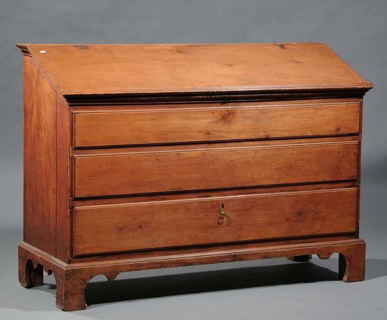 Lift-top desk, pine, with one drawer below two false drawers – a rare form. The desk has an attractive Chippendale bracket base, a slant lid with a raised molded edge and a till inside with a drawer beneath. The desk sports hand-forged hinges and is