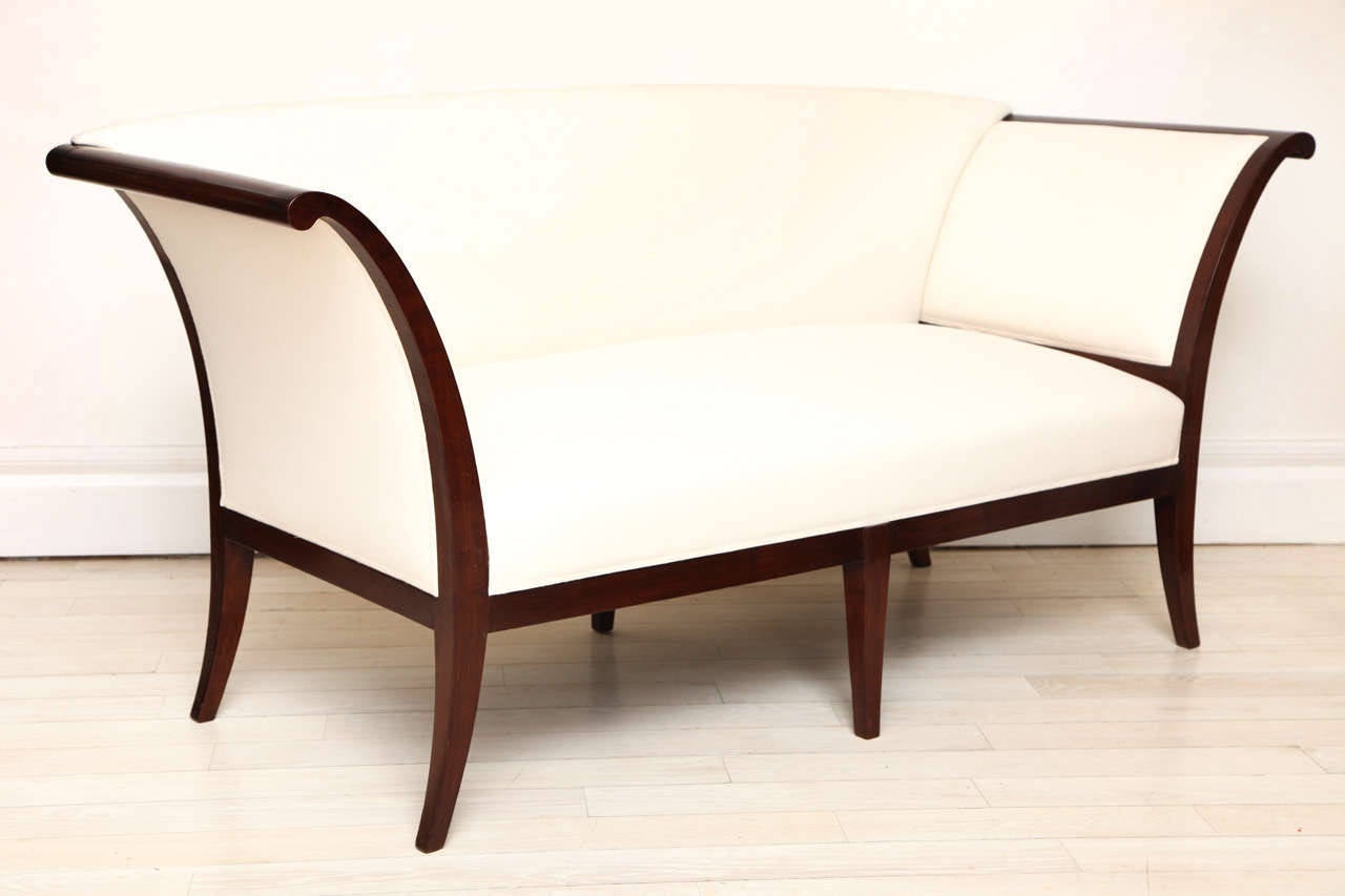 Cherry settee with flared arms and tapered legs.