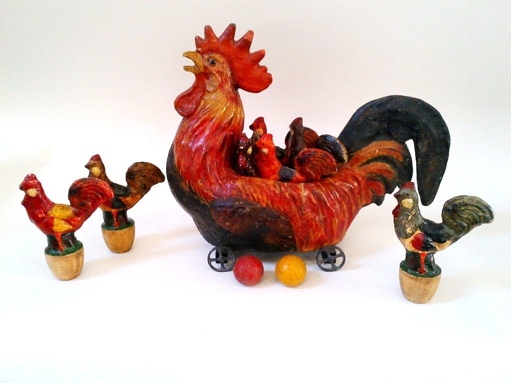 Colorful papier-mache rooster with 7 chicken skittles.  Rarely found, the rooster is hollow and has iron wheels and glass eyes.  The chicks are also papier-mache with wooden bases. 2 wooden balls accompany this wonderful toy.  The chicks are seven