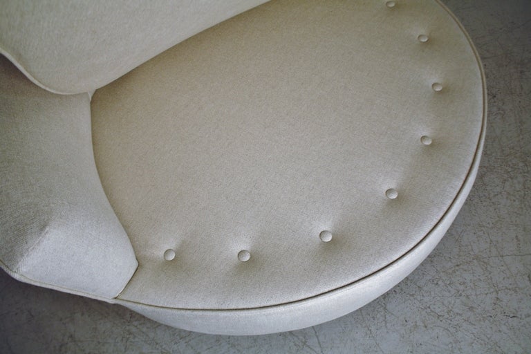 Large round lounge chair on castors in the style of Milo Baughman meticulously reupholstered in a luxurious Italian textile of viscose/linen/cotton blend in ivory with a melange of pale gray undertones.  New cushions and tufted pillows complete the