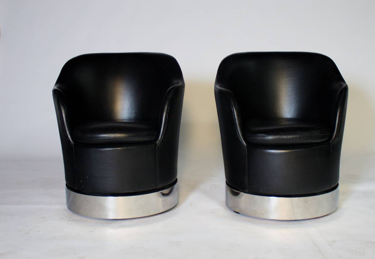 Original pair of 1970s black leather swivel chairs by Phillip Enfield, N.Y. on polished steel base and concealed castors. These chairs swivel, rock and roll smoothly on concealed castors.