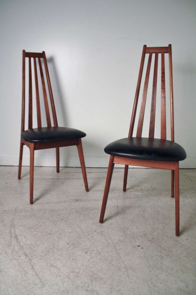 Pair of teak high-back Danish Modern dining chairs with original black vinyl seats.  In the style of the 